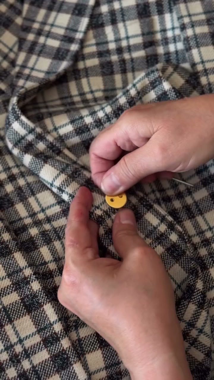 Hands working on a gold button
